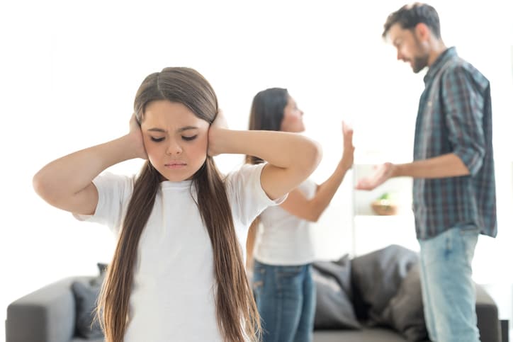 Child covering ears as parents who are in the divorce process argue.
